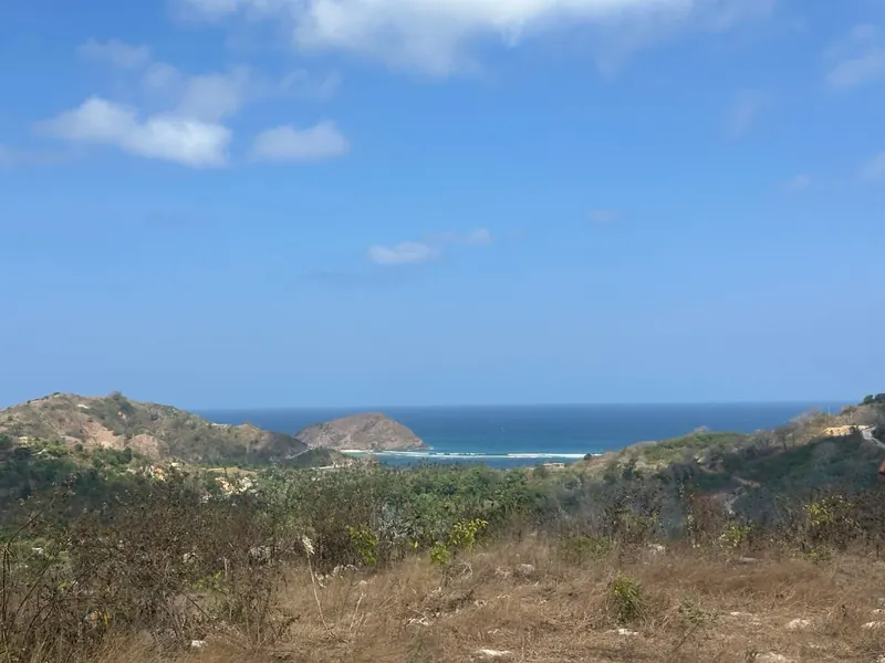 Foto desde la parcela: la ladera baja hasta la playa de Areguling y su islote